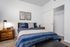 Cozy bedroom featuring a plush bed with navy striped bedding, stylish wood nightstand, and spacious closet.
