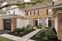 Charming brick townhouse with a stylish pergola and lush landscaping, enhancing curb appeal and elegance.