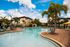 Luxurious apartment complex featuring a stunning outdoor pool surrounded by palm trees and modern lounge chairs, perfect for relaxation.