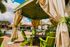 Inviting outdoor lounge with vibrant green chairs under a luxurious gazebo beside a sparkling pool in a sunny courtyard.