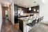 Modern kitchen showcasing sleek dark cabinets, a spacious granite island with seating, and stylish lighting, perfect for entertaining.