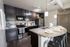 Modern kitchen with sleek dark cabinetry, stainless steel appliances, and a stylish island with seating for three, perfect for contemporary living.