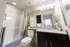 Modern bathroom featuring a sleek granite countertop, elegant dark cabinets, and a cozy bathtub with stylish decor.