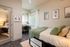 Cozy bedroom with modern design, featuring a stylish bed, soft green accents, artistic wall decor, and a bright home office nook.