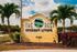 Inviting entrance sign for The Reef Student Living surrounded by vibrant palm trees and lush landscape, offering a tropical atmosphere.
