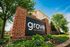 Inviting entrance to Grove at 1407 S Grand Avenue, featuring well-maintained landscaping and vibrant greenery under a bright blue sky.