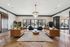 Elegant living room with stylish leather sofas, chic chandelier, and large windows offering natural light on beautiful wood flooring.