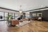 Elegant apartment lounge with chic brown leather sofas, large windows, natural light, and a stunning chandelier.