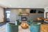 Chic and inviting lounge area featuring plush green chairs, a stylish wooden coffee table, and a cozy brick fireplace with modern decor.
