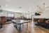 Spacious recreation room featuring a ping pong table, cozy seating booths, elegant bar with pendant lighting, and hardwood flooring.