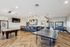 Inviting recreational room featuring a sleek pool table, modern ping pong setup, stylish bar seating, and chic lighting, perfect for entertainment.