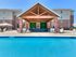 Inviting outdoor patio with modern furniture overlooking a sparkling swimming pool, perfect for relaxation and entertainment.