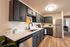 Modern kitchen with sleek dark cabinetry, stainless steel appliances, and elegant hardwood flooring, offering a chic and functional cooking space.