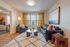 Chic and cozy living room with plush seating, colorful cushions, and a stylish coffee table, bathed in natural light from large windows.