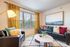 Bright and inviting living room with elegant decor, featuring a cozy seating arrangement, vibrant pillows, and a large window with stylish curtains.