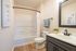 Elegant bathroom with a modern vanity, stylish mirror, and inviting bathtub, complemented by tasteful decor and wood-style flooring.