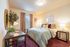 Inviting bedroom with elegant decor, cozy bed, stylish desk, and abundant natural light from large window.