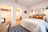 Cozy bedroom featuring a plush bed with accent pillows, modern lighting, spacious closet, and adjacent bathroom.