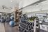 Modern fitness center with state-of-the-art equipment, featuring treadmills, weight racks, and exercise balls in a bright, airy space with large windows.