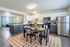 Contemporary open kitchen and dining area with sleek white cabinetry, modern appliances, and elegant dining setup on a patterned rug.