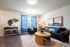 Inviting living room with modern decor, featuring a plush sofa, vibrant cushions, and natural light through elegant blue curtains.