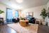 Bright and inviting living room with stylish decor, cozy seating, and large windows accentuated by sheer blue curtains.