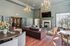 Elegant and spacious living area featuring high ceilings, chandeliers, a cozy fireplace, and comfortable seating, perfect for entertaining.