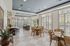 Elegant dining area featuring large windows with plantation shutters, stylish lighting fixtures, and modern wooden tables.