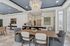 Elegant dining area with chic chandelier, cozy seating, and stylish open-plan kitchen featuring modern lighting and sleek countertops.
