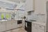 Bright and modern kitchen with sleek white cabinetry, stylish pendant lighting, and elegant tile backsplash.
