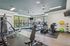 Bright and modern fitness center equipped with cardio machines, strength training equipment, and vibrant exercise balls with large windows providing natural light.