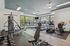 Modern fitness center with state-of-the-art equipment, large windows for natural light, and sleek wood flooring.