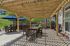 Charming outdoor patio with wooden pergola, cozy seating, and vibrant blue umbrellas, perfect for relaxation and gatherings.