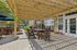 Charming outdoor patio with wooden pergola, dining set, and lush greenery, perfect for entertaining and relaxation.