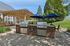 Inviting outdoor space with dual stainless steel grills, shaded seating under blue umbrellas and a charming wooden pergola, ideal for entertaining.