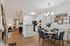 Inviting open-plan living and dining area with elegant wooden flooring, featuring a cozy seating arrangement, modern kitchen, and stylish wall decor.