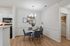 Elegant dining area with modern decor, featuring a round table set with stylish place settings and surrounded by plush blue chairs, open to a contemporary kitchen.