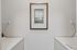 Chic laundry room with modern washing appliances and elegant framed artwork, complemented by clean, white shelving.