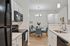 Sleek kitchen and dining area with modern appliances, elegant white cabinetry, and inviting dining table for four.