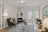 Charming living room with elegant fireplace, cozy seating, and natural light streaming through glass doors leading to a serene balcony view.