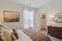 Inviting bedroom with elegant decor, a plush bed, and a spacious walk-in closet, accented by warm lighting and stylish artwork.