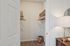 Inviting walk-in closet with organized shelving and warm lighting, perfect for extra storage space.