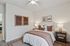 Cozy bedroom with modern decor, featuring a plush bed with warm, textured pillows, elegant bedside lamps, and captivating artwork on the walls.