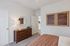 Inviting bedroom with elegant wooden dresser, chic round mirror, and contemporary artwork for a cozy atmosphere.