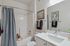 Elegant bathroom with a modern white vanity, stylish chrome fixtures, and a cozy bathtub adorned with tasteful artwork and plush towels.