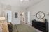 Bright and inviting bedroom featuring elegant decor with a plush bed, stylish black dresser, and a spacious walk-in closet.