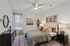 Elegant bedroom featuring a cozy bed with plush pillows, stylish decor, and ample natural light from a large window, creating a serene and inviting space.