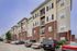Modern multi-story apartment building with brick facade and ample parking, showcasing urban living with style and convenience.