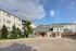 Inviting apartment complex exterior showcasing elegant architecture, lush greenery, and a bright blue sky backdrop, perfect for comfortable living.
