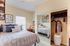 Cozy bedroom with stylish decor, featuring a spacious bed with patterned bedding, playful wall art, and a mirrored closet door reflecting the organized storage space.